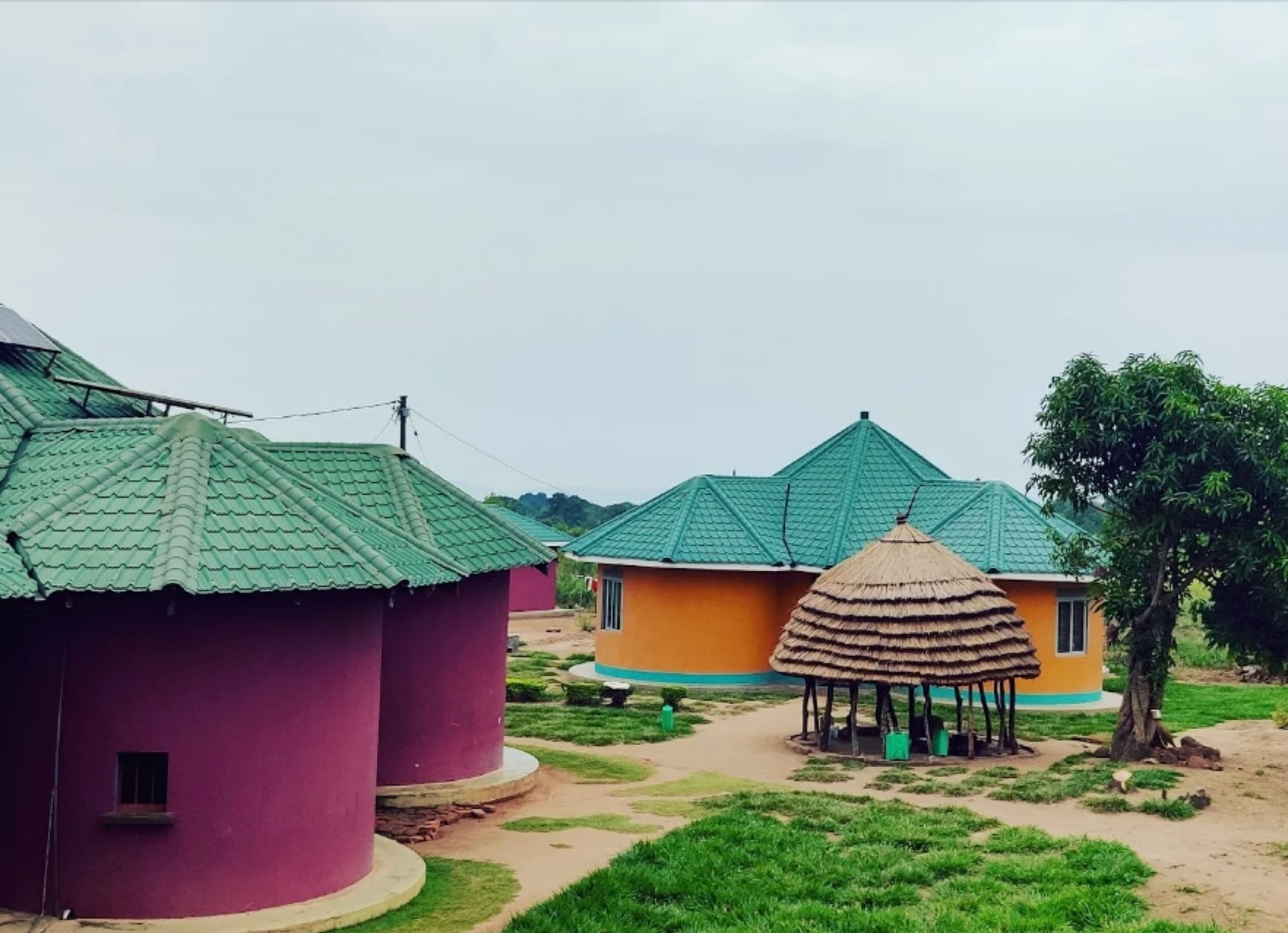 The round, brightly painted buildings of the Ot Nywal Me Kuc birth center under a wide sky
