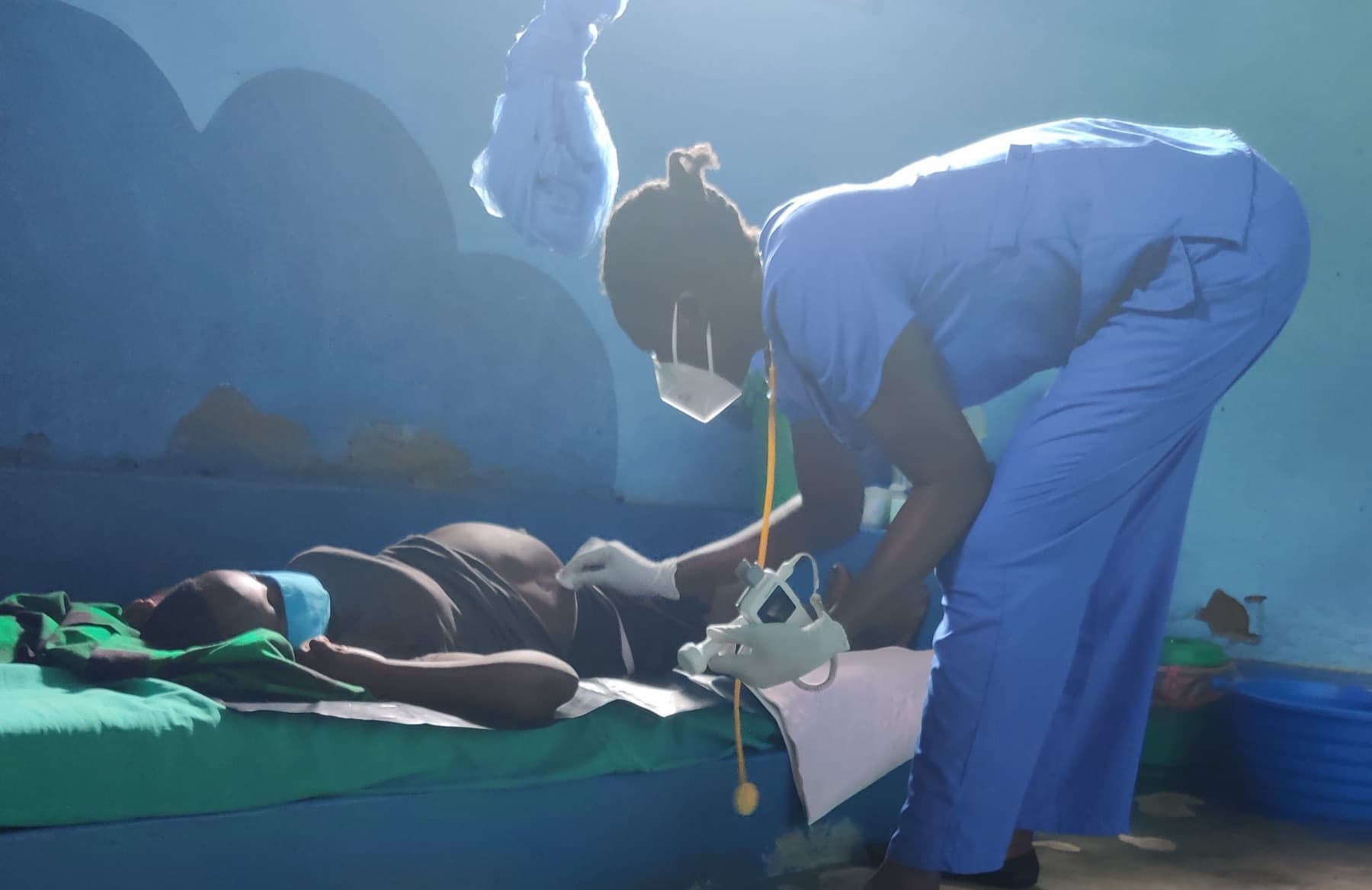 A midwife in blue scrubs caring for a mother at the Atiak birth center