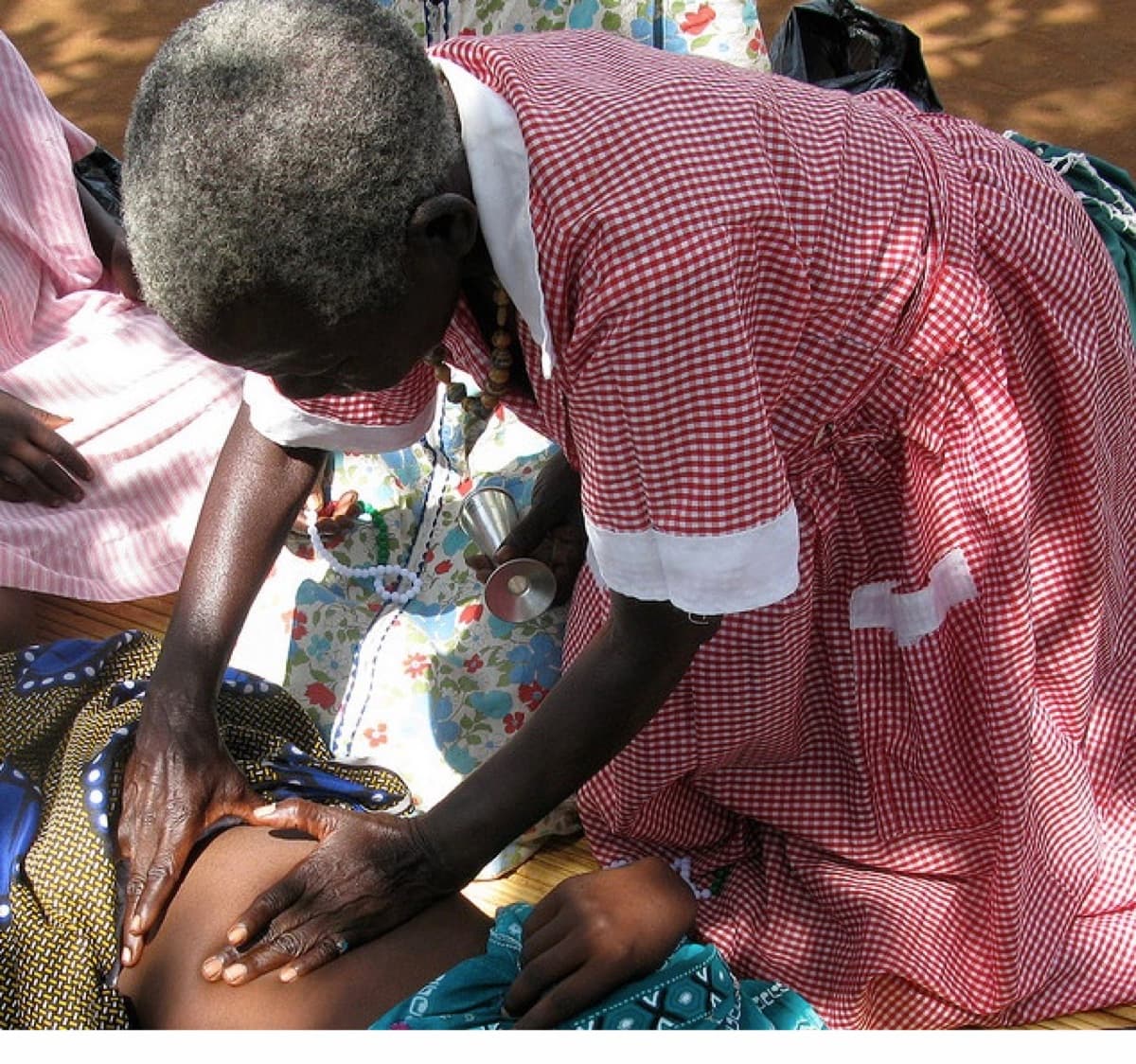 A traditional midwife palpating a pregnant woman’s belly