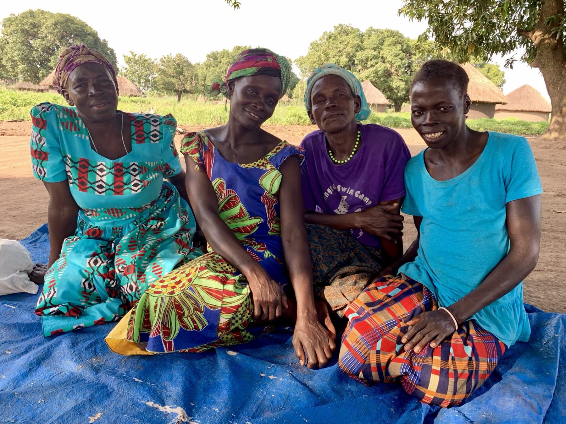 Women from the Atiak community sitting together in bright dresses